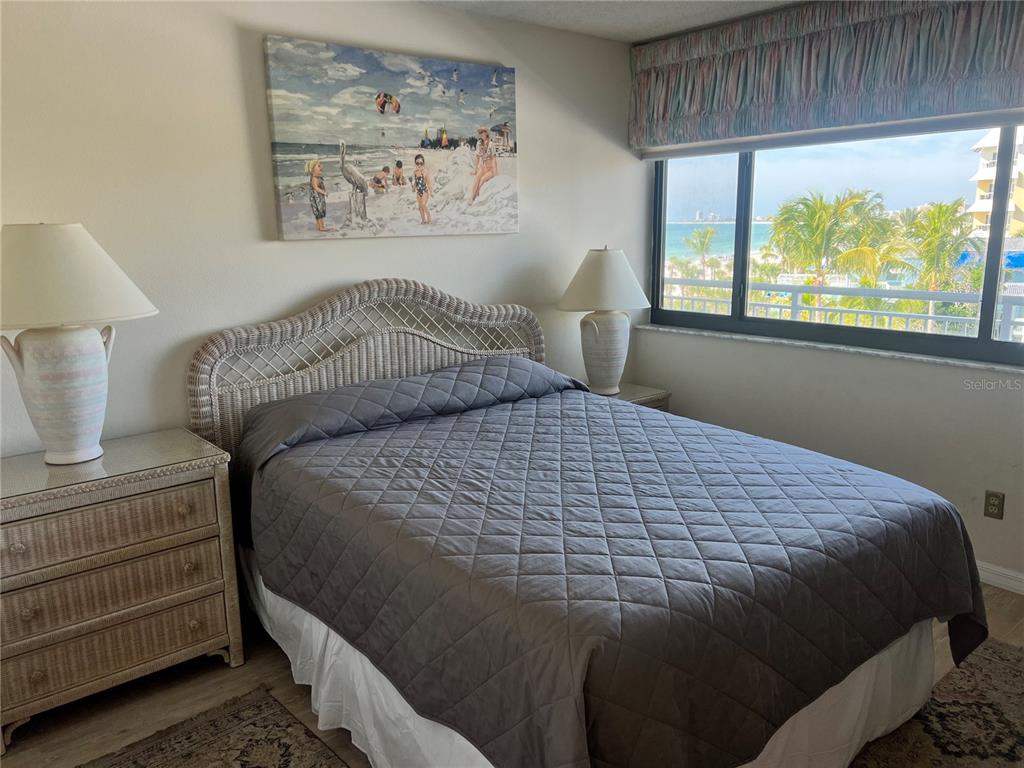 A bedroom features a wicker headboard, a quilted gray bedspread, and a beach view window — 1001 POINT OF ROCKS ROAD UNIT 508, SARASOTA, FL