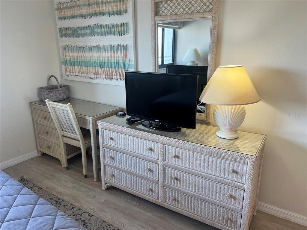 A bedroom features a wicker dresser, a matching desk with a chair, and a table lamp — 1001 POINT OF ROCKS ROAD UNIT 508, SARASOTA, FL