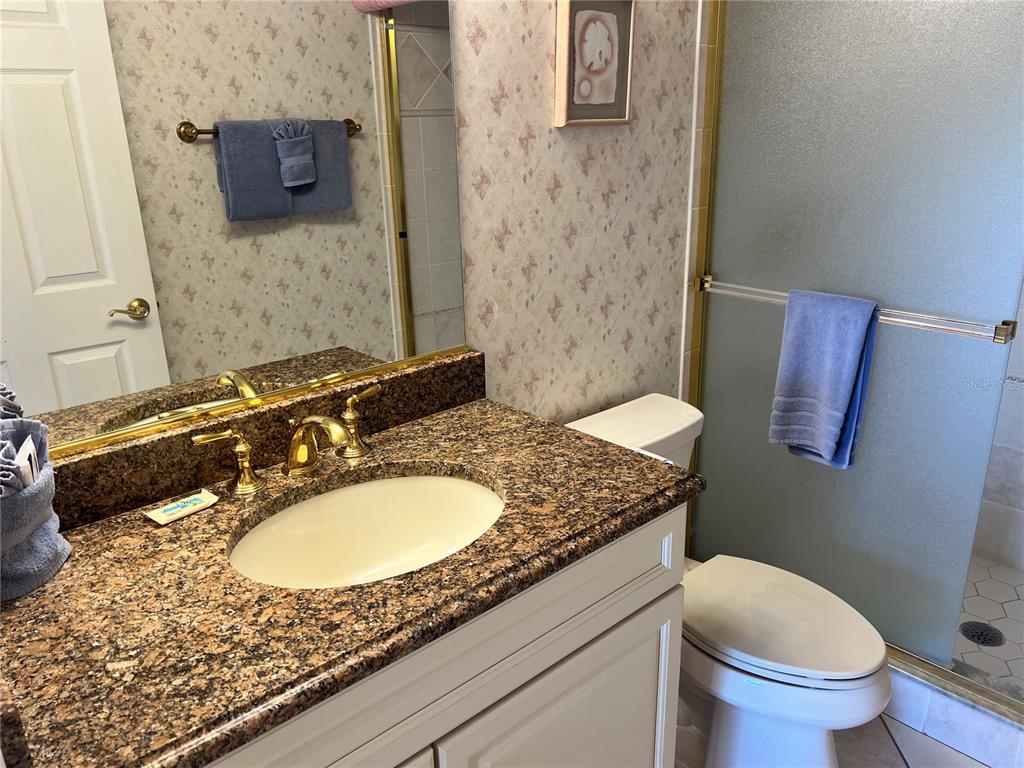 A bathroom features a granite vanity, white cabinet, toilet, and a glass-enclosed shower — 1001 POINT OF ROCKS ROAD UNIT 508, SARASOTA, FL