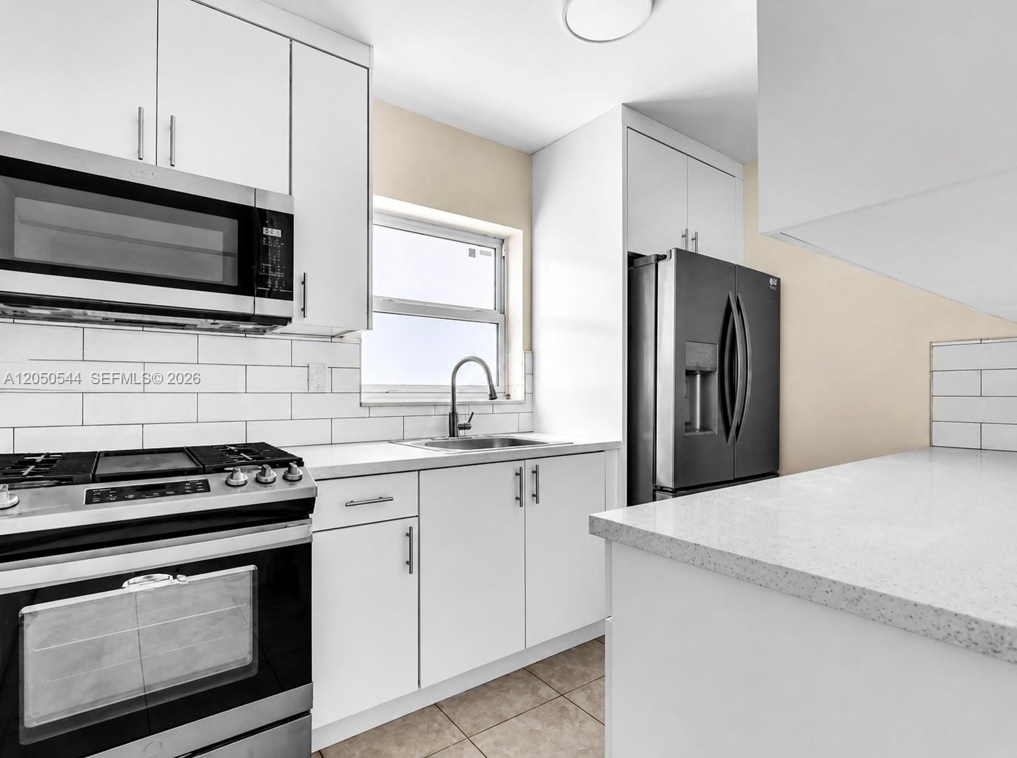 A kitchen features white cabinets, stainless steel appliances, a subway tile backsplash, and quartz countertops — 1245 W 24th St # 219, Hialeah FL 33010, HIALEAH, FL