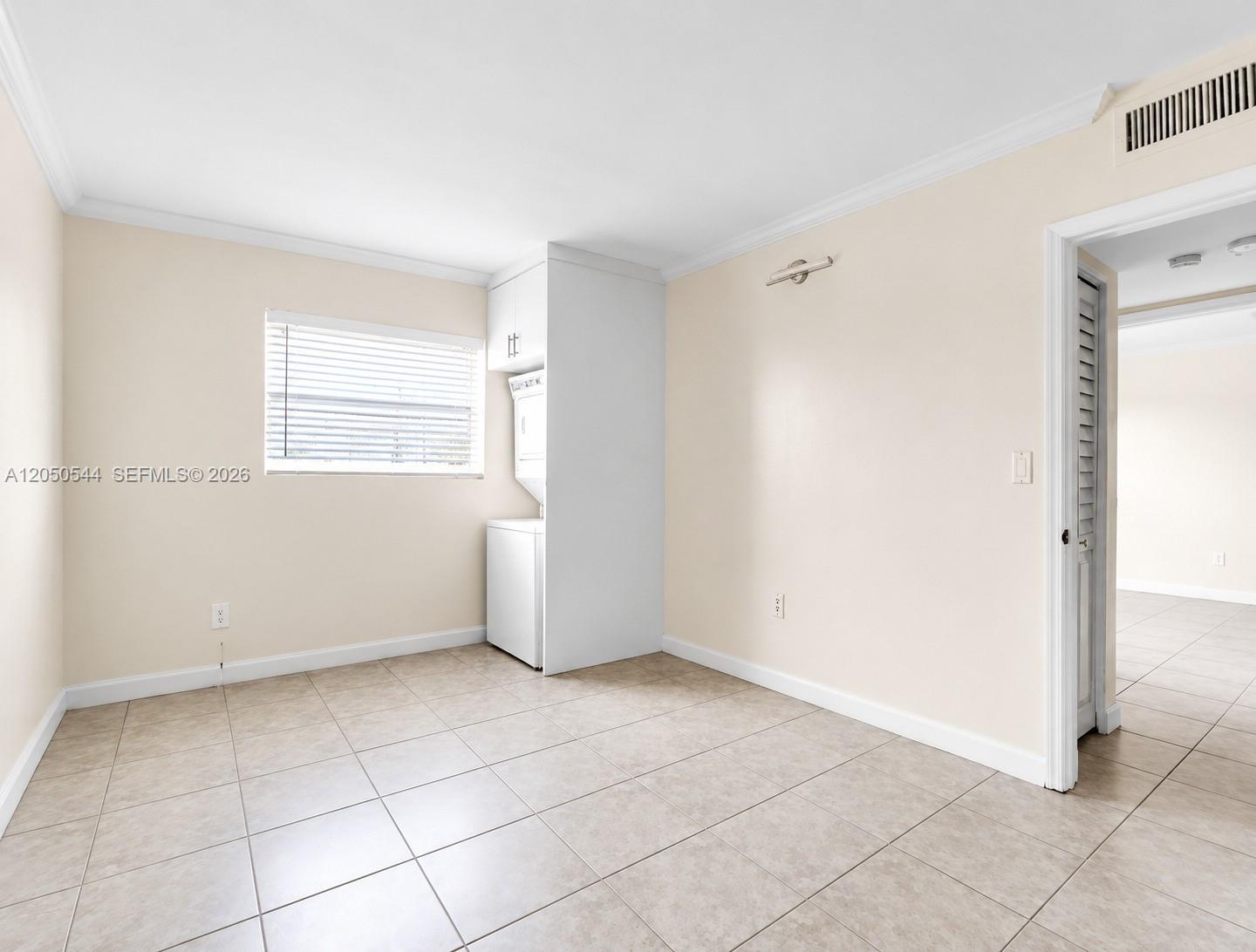 A room with tile flooring, beige walls, and a built-in laundry unit by a window — 1245 W 24th St # 219, Hialeah FL 33010, HIALEAH, FL