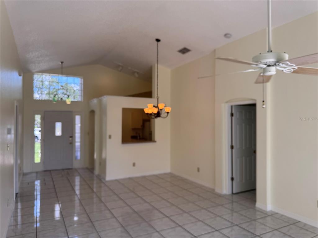 An interior view of a living area with vaulted ceilings, tiled floors, and two light fixtures — 7872 ELMSTONE CIRCLE, ORLANDO, FL