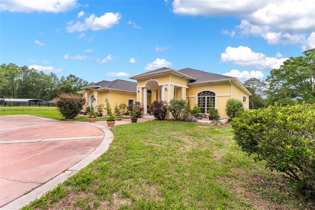 A yellow single-story house with a circular driveway and a covered front entryway — 15510 SW 149TH PLACE, ARCHER, FL