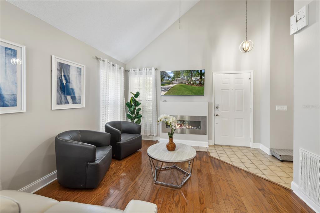 A living room features a vaulted ceiling, hardwood floors, a fireplace, and two leather chairs — 938 SOUTHRIDGE TRAIL, ALTAMONTE SPRINGS, FL