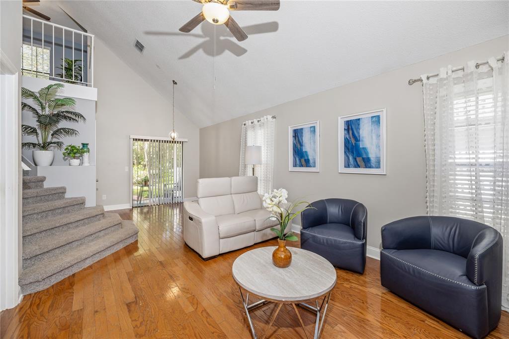 A living room with hardwood floors, a vaulted ceiling, a staircase, and leather seating — 938 SOUTHRIDGE TRAIL, ALTAMONTE SPRINGS, FL
