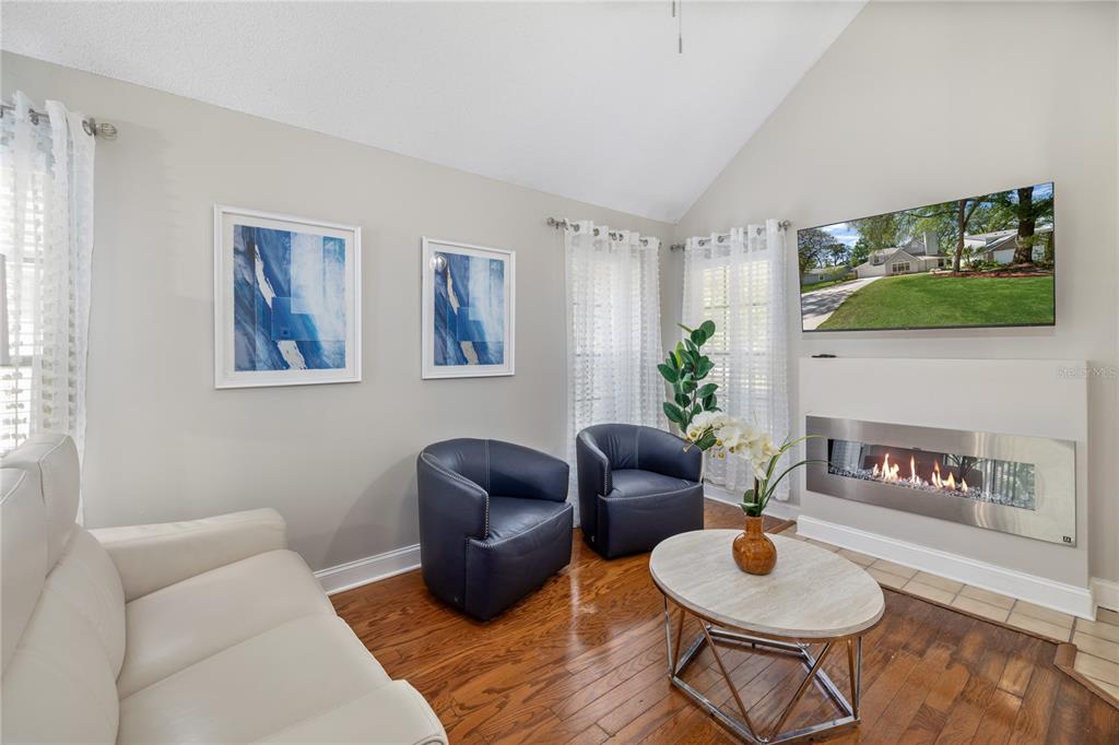 A living room features a white sofa, two navy armchairs, a fireplace, and a television — 938 SOUTHRIDGE TRAIL, ALTAMONTE SPRINGS, FL