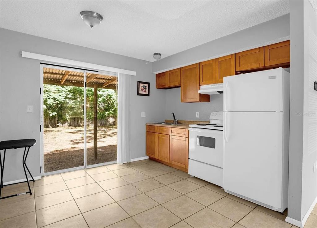 A kitchen with light wood cabinets, white appliances, and a sliding glass door to a yard — 15115 OMAHA STREET, HUDSON, FL
