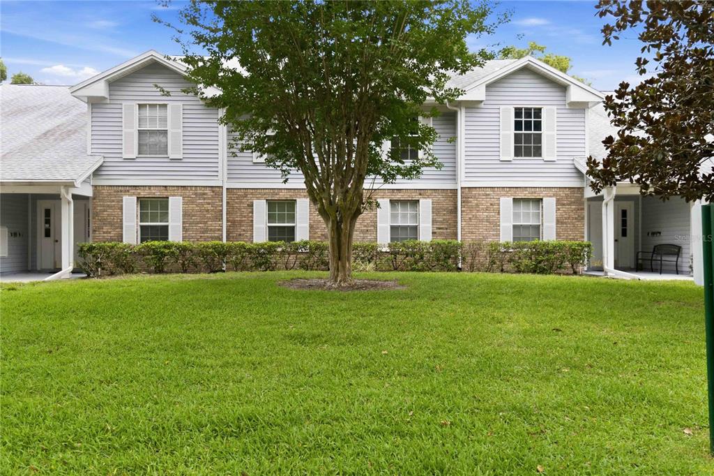 A two-story townhouse exterior with light blue siding, brick lower walls, and a front lawn — 5278 WHITSTABLE WAY UNIT 5, ORLANDO, FL