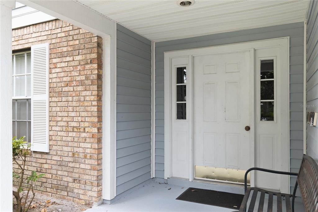 A covered front porch features a white door with sidelights and gray horizontal siding — 5278 WHITSTABLE WAY UNIT 5, ORLANDO, FL