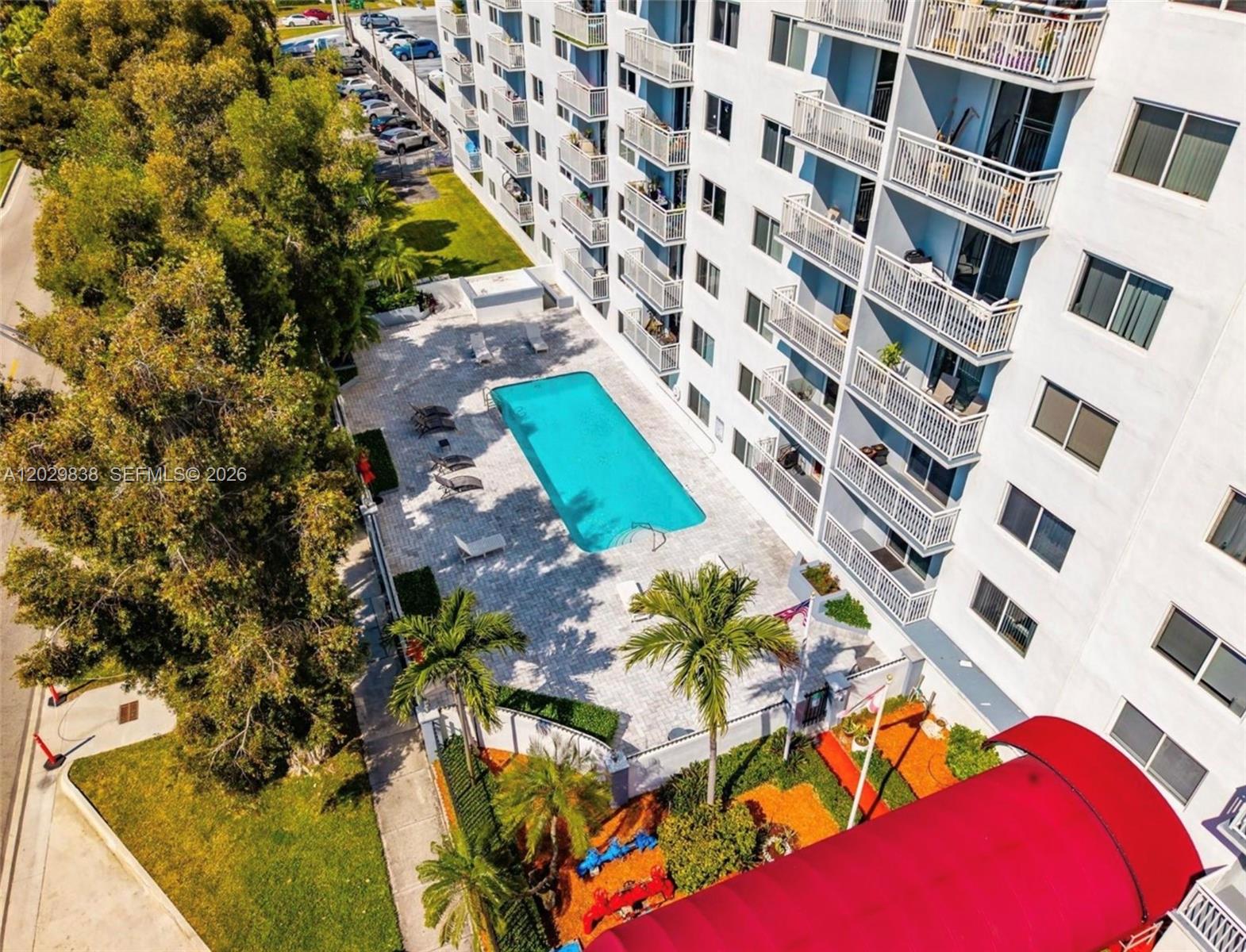 An aerial view shows a rectangular swimming pool on a patio next to a building — 1251 NE 108th St # 617, Miami FL 33161, MIAMI, FL