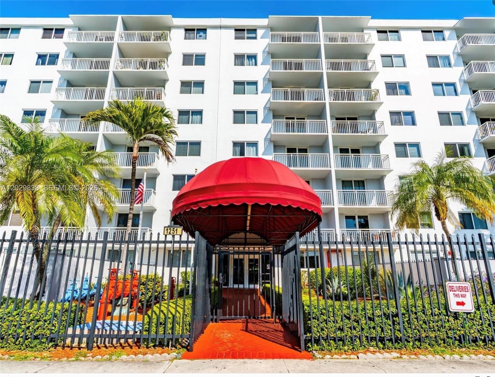 A multi-story white apartment building features a prominent red awning over the front entrance — 1251 NE 108th St # 617, Miami FL 33161, MIAMI, FL