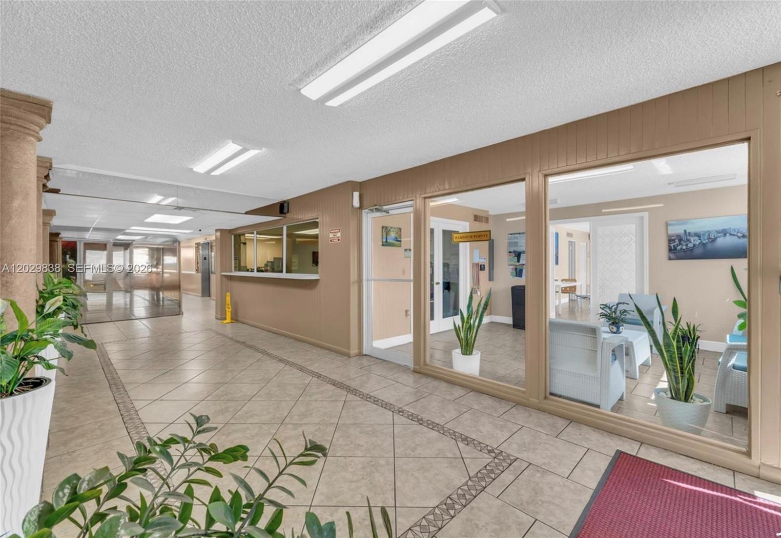 A tiled lobby features a reception window, glass-walled office, and indoor potted plants — 1251 NE 108th St # 617, Miami FL 33161, MIAMI, FL