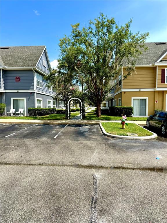 An exterior view shows two apartment buildings separated by a tree-lined walkway with an arched gate — 2606 LODI CIRCLE UNIT 105, KISSIMMEE, FL