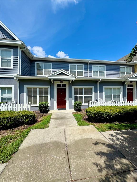 A two-story townhouse with blue siding, a red front door, and a white picket fence — 2606 LODI CIRCLE UNIT 105, KISSIMMEE, FL