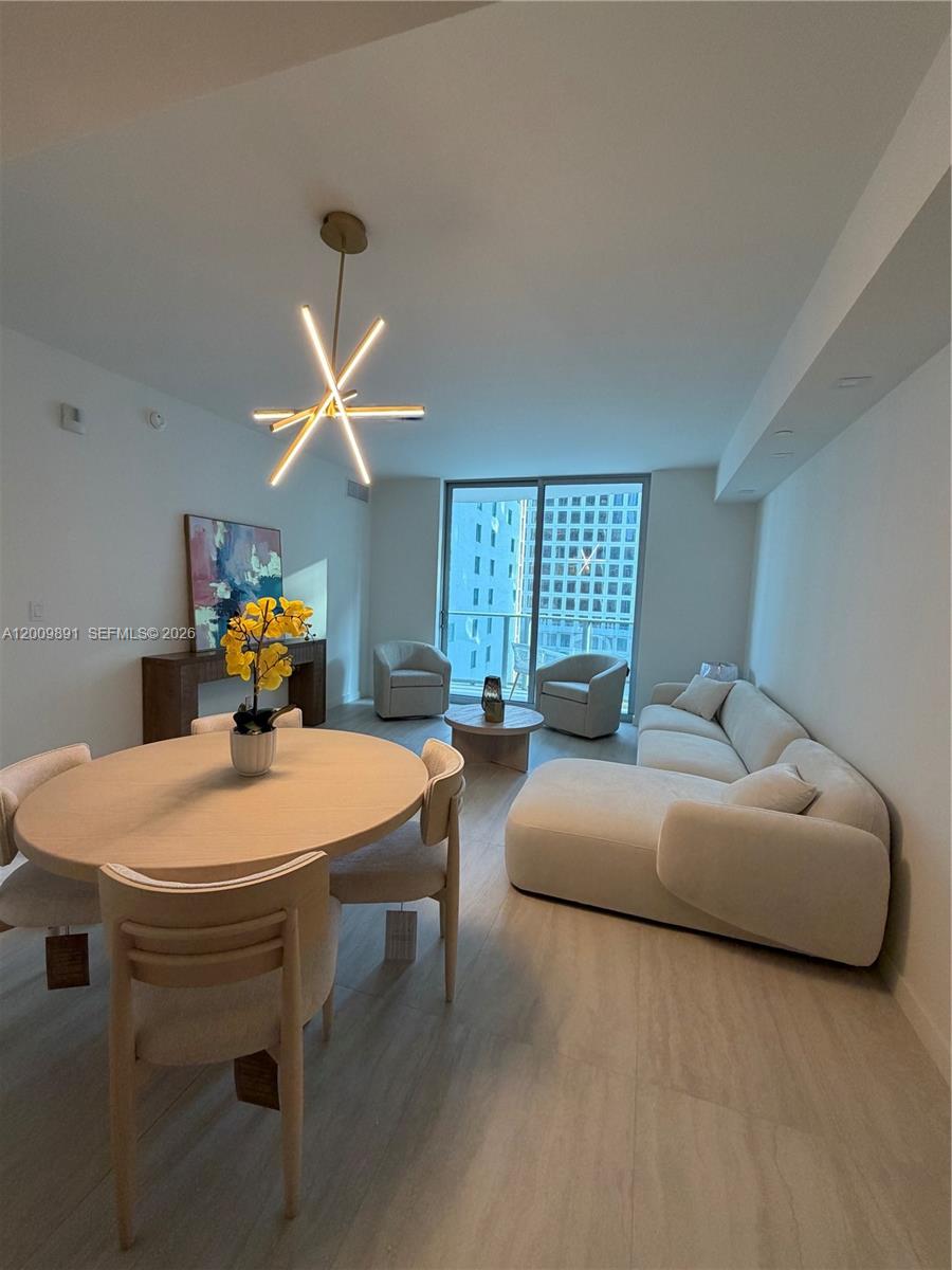 A modern living and dining area features light wood furniture, a sectional sofa, and floor-to-ceiling windows — 77 SE 5th street # 1614, Miami FL 33131, MIAMI, FL