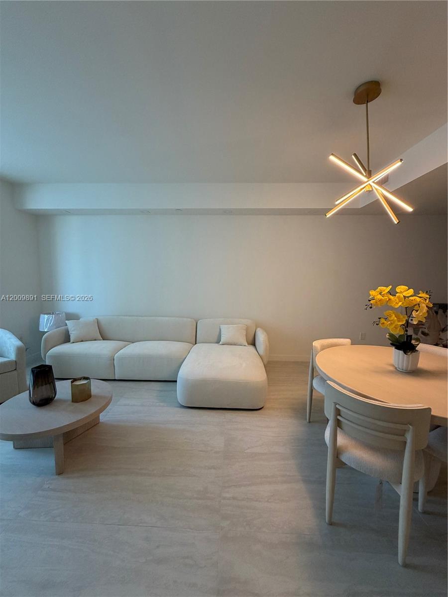 A modern living and dining area features a white sectional sofa and light wood furniture — 77 SE 5th street # 1614, Miami FL 33131, MIAMI, FL