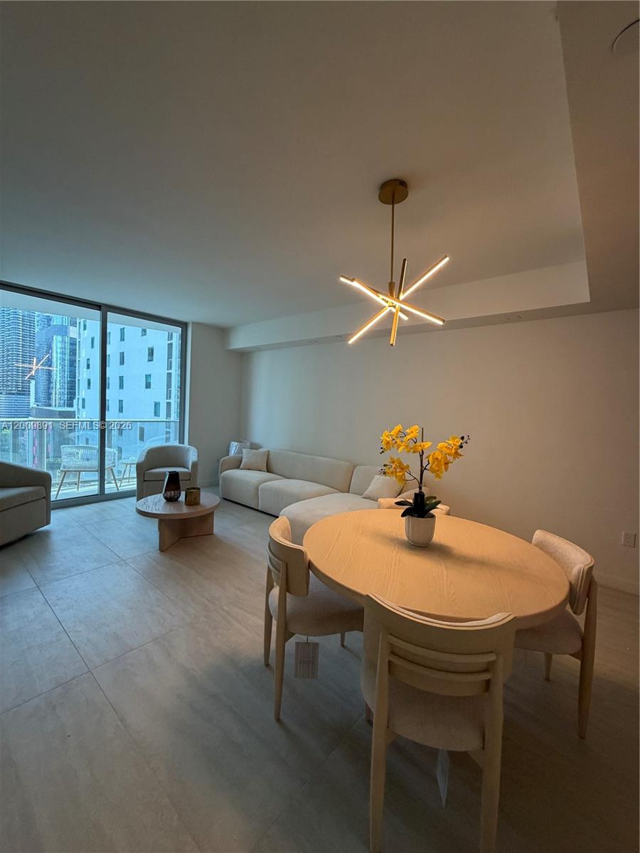 A modern living and dining area features light tile floors, neutral furniture, and floor-to-ceiling windows — 77 SE 5th street # 1614, Miami FL 33131, MIAMI, FL