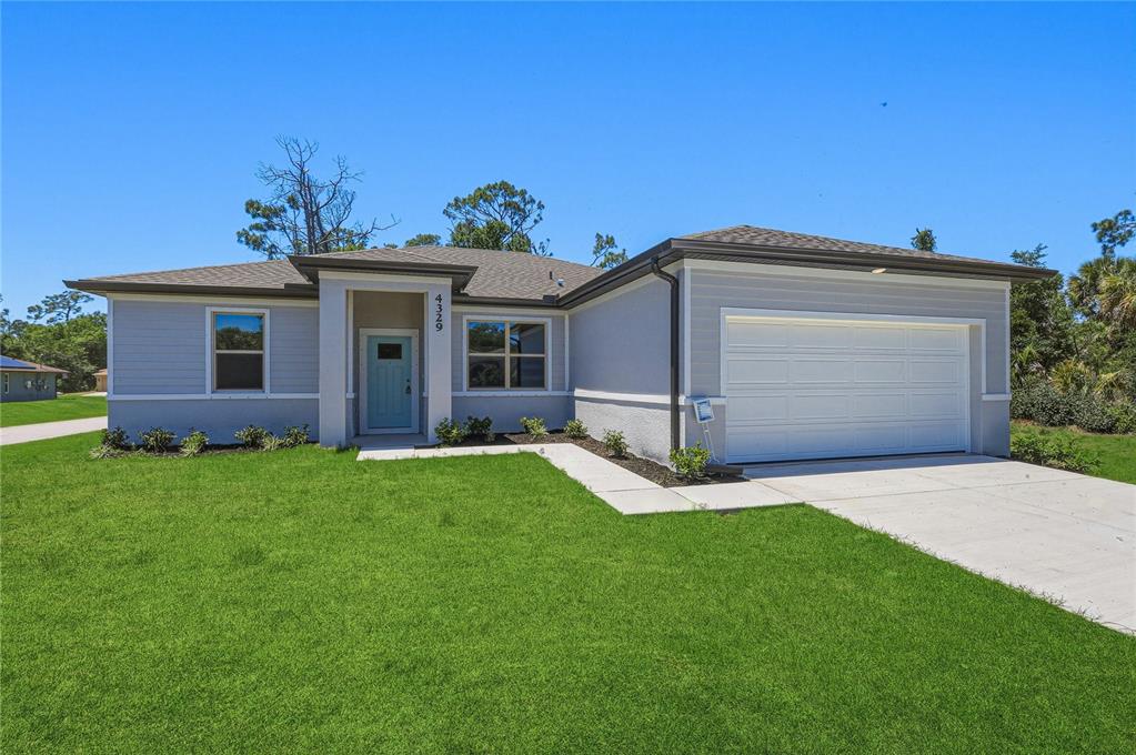 A single-story house with light gray siding, a white garage door, and a blue door — 1459 N CHAMBERLAIN BOULEVARD, NORTH PORT, FL