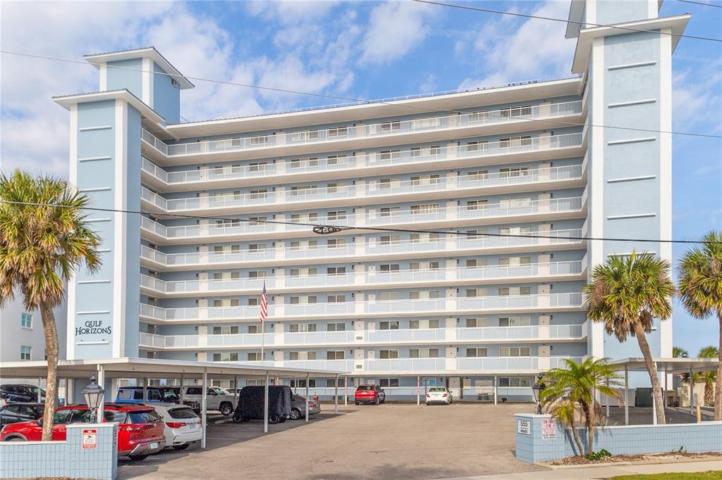 A multi-story blue apartment building with balconies and a covered parking area in front — 555 THE ESPLANADE N UNIT 1003, VENICE, FL