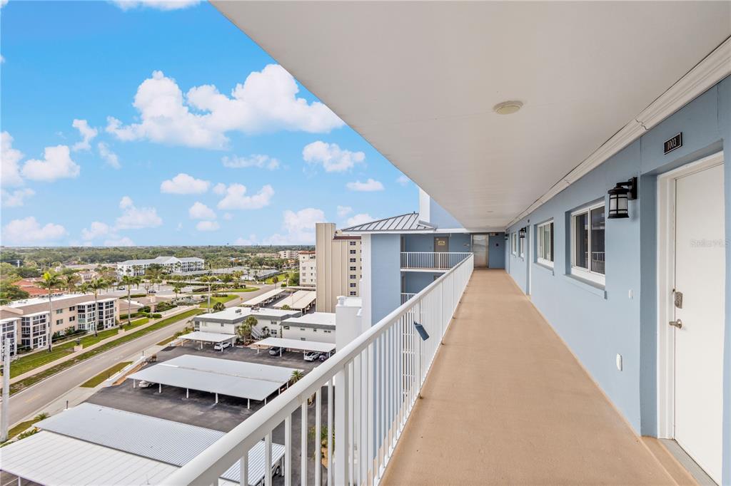 An elevated outdoor walkway overlooks a parking lot and surrounding residential buildings — 555 THE ESPLANADE N UNIT 1003, VENICE, FL