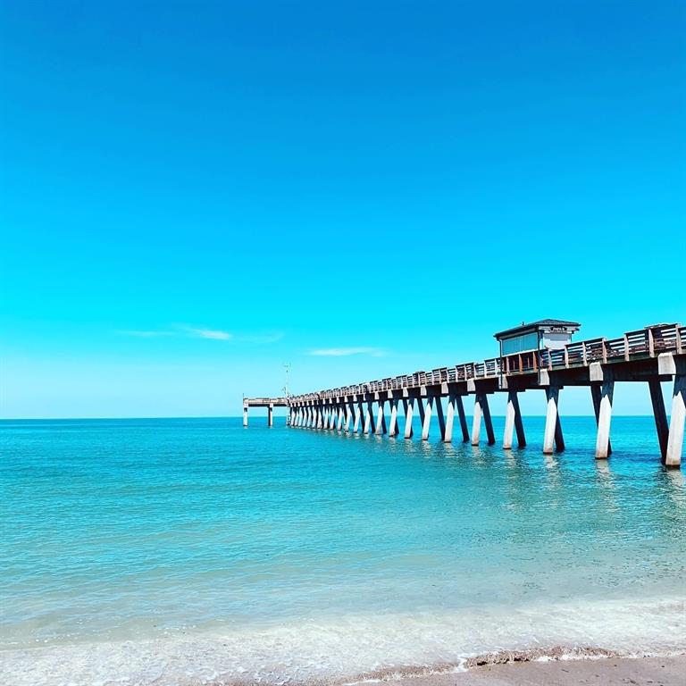 A long wooden pier extends over turquoise ocean water under a clear blue sky — HADER ROAD, NORTH PORT, FL