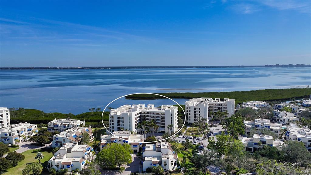 An aerial view shows a multi-story white apartment building surrounded by smaller residential units — 1932 HARBOURSIDE DRIVE UNIT 244, LONGBOAT KEY, FL