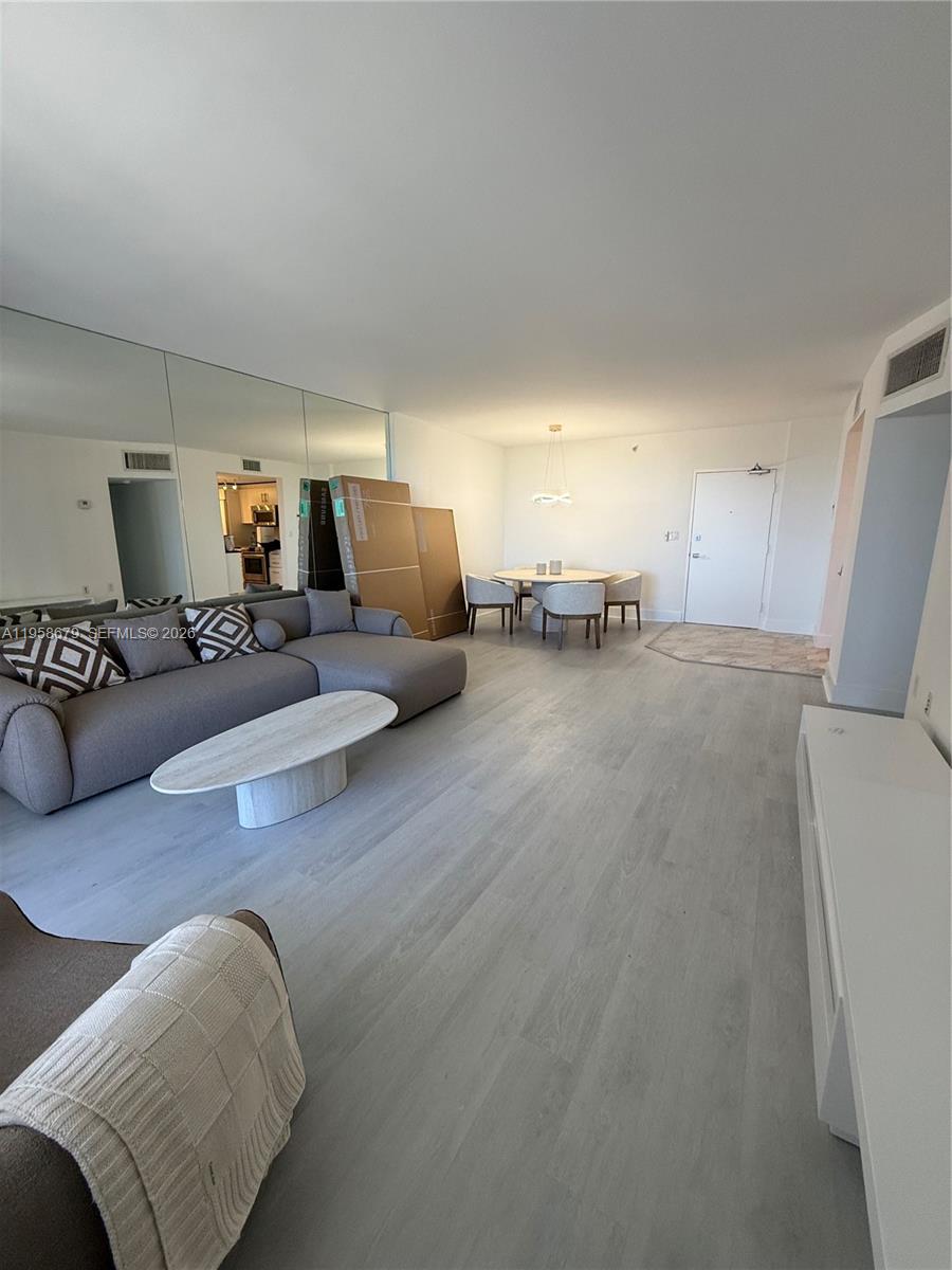 A living room features light wood-look flooring, a gray sectional sofa, and a dining area — 10275 Collins Ave # 420, Bal Harbour FL 33154, BAL HARBOUR, FL