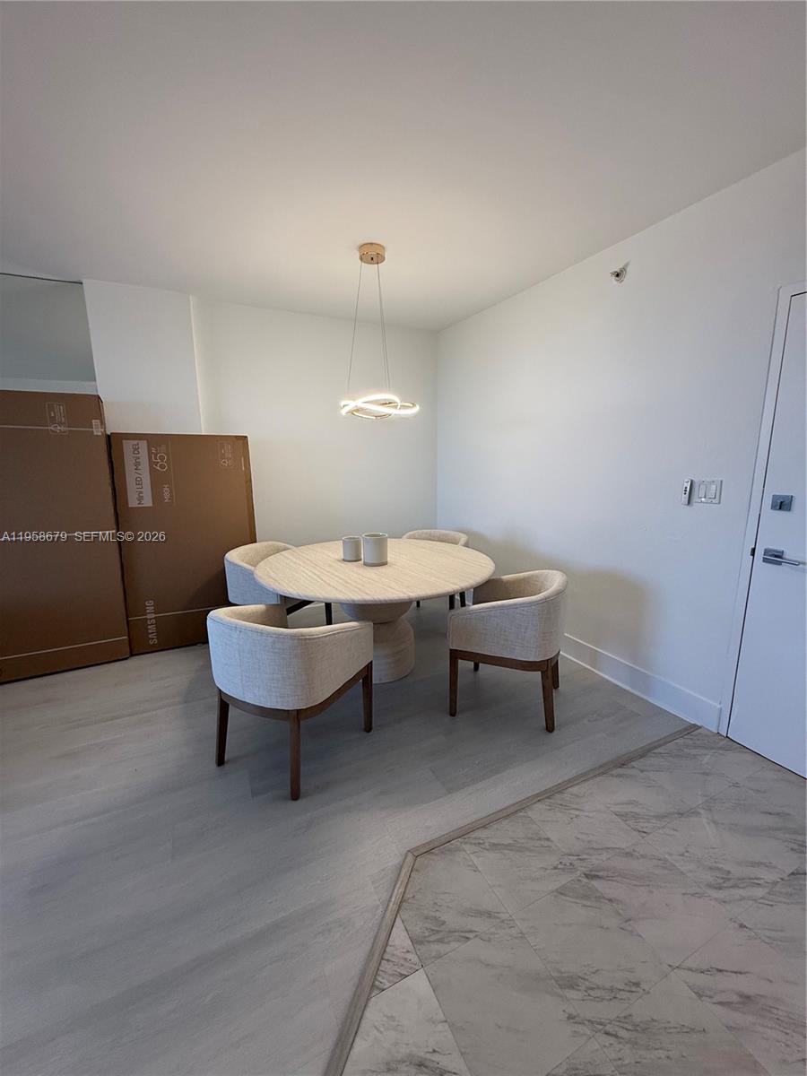 A dining area features a round table with four upholstered chairs under a modern pendant light — 10275 Collins Ave # 420, Bal Harbour FL 33154, BAL HARBOUR, FL