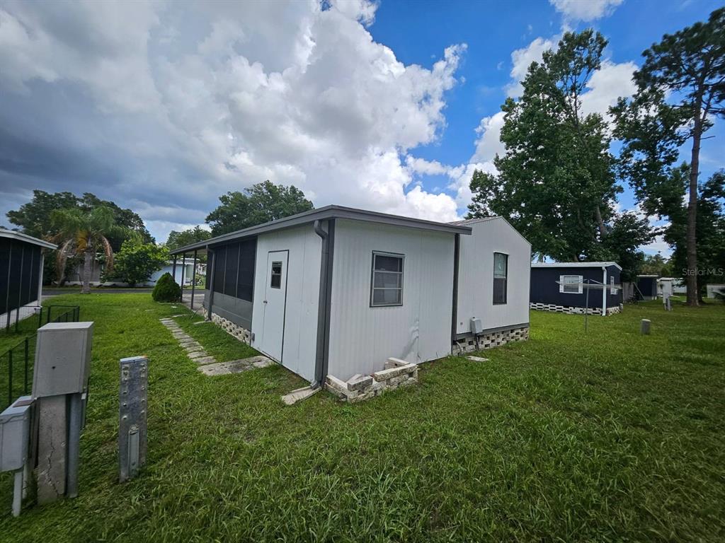 A side view of a white mobile home with a screened porch and grassy yard — 6445 BELLE TERRE, NEW PORT RICHEY, FL