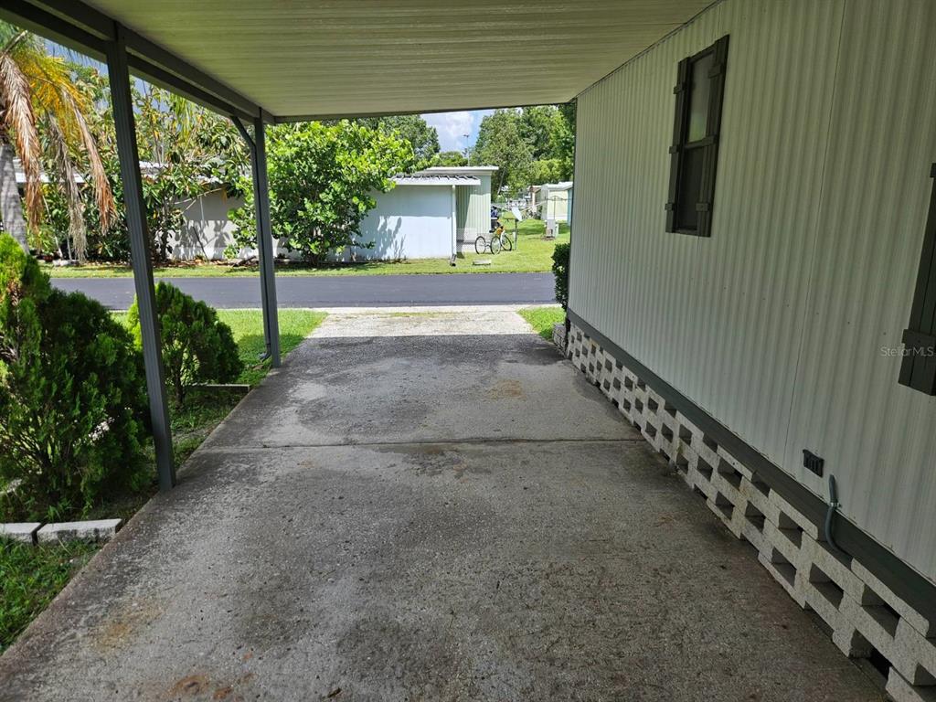 A concrete carport with a metal roof attached to the side of a mobile home — 6445 BELLE TERRE, NEW PORT RICHEY, FL