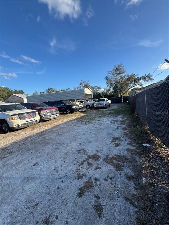 A gravel lot features a metal carport sheltering several parked pickup trucks and vehicles — 1050 NURSERY ROAD, WINTER SPRINGS, FL