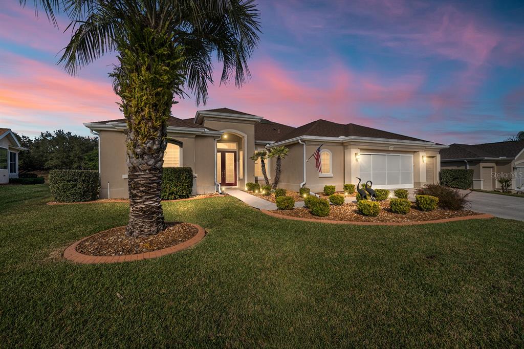 A single-story stucco house with a palm tree, a landscaped front yard, and a garage — 9479 SE 130TH STREET ROAD, SUMMERFIELD, FL