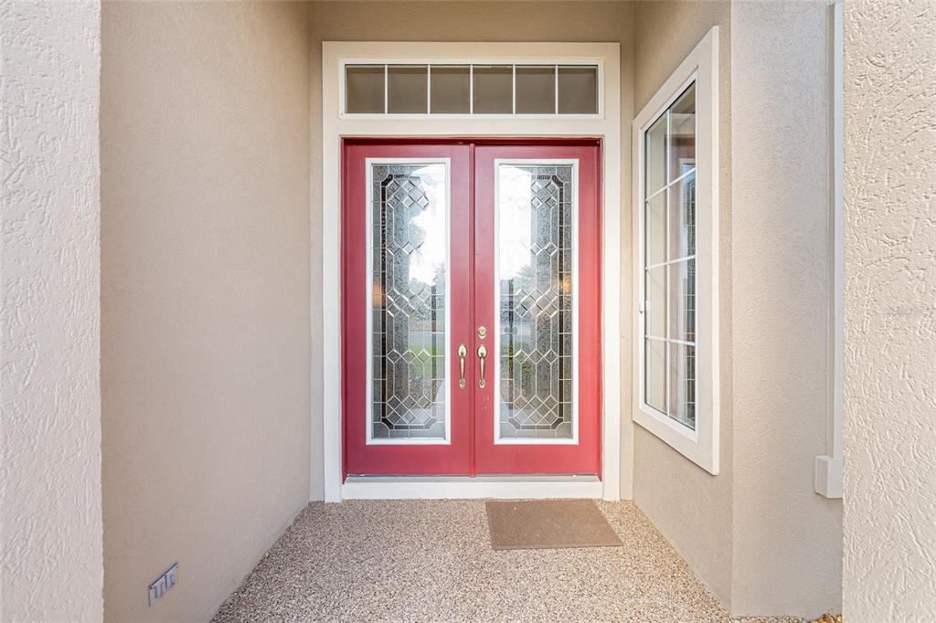 A red double front door with glass inserts sits in a covered entryway — 9479 SE 130TH STREET ROAD, SUMMERFIELD, FL