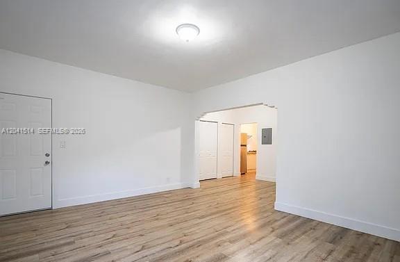 A bright, empty room with white walls, light wood-look flooring, and a doorway to a kitchen — 245 79th Street # 2, Miami Beach FL 33141, MIAMI BEACH, FL