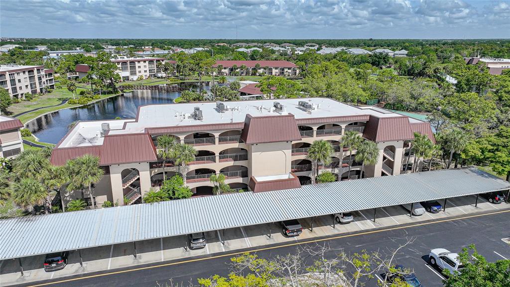 An aerial view shows a multi-story apartment building with a metal-roofed carport in front — 23465 HARBORVIEW ROAD UNIT 616, PUNTA GORDA, FL