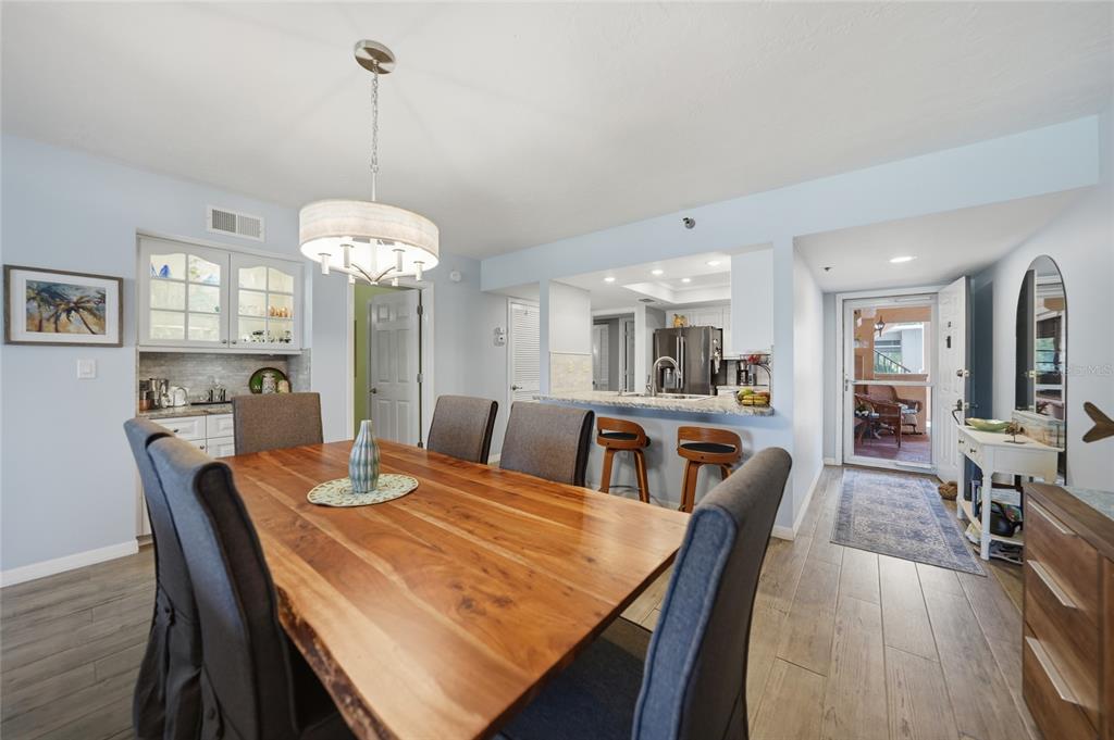 A dining room with a live-edge wood table, gray chairs, and an adjacent kitchen bar — 23465 HARBORVIEW ROAD UNIT 616, PUNTA GORDA, FL