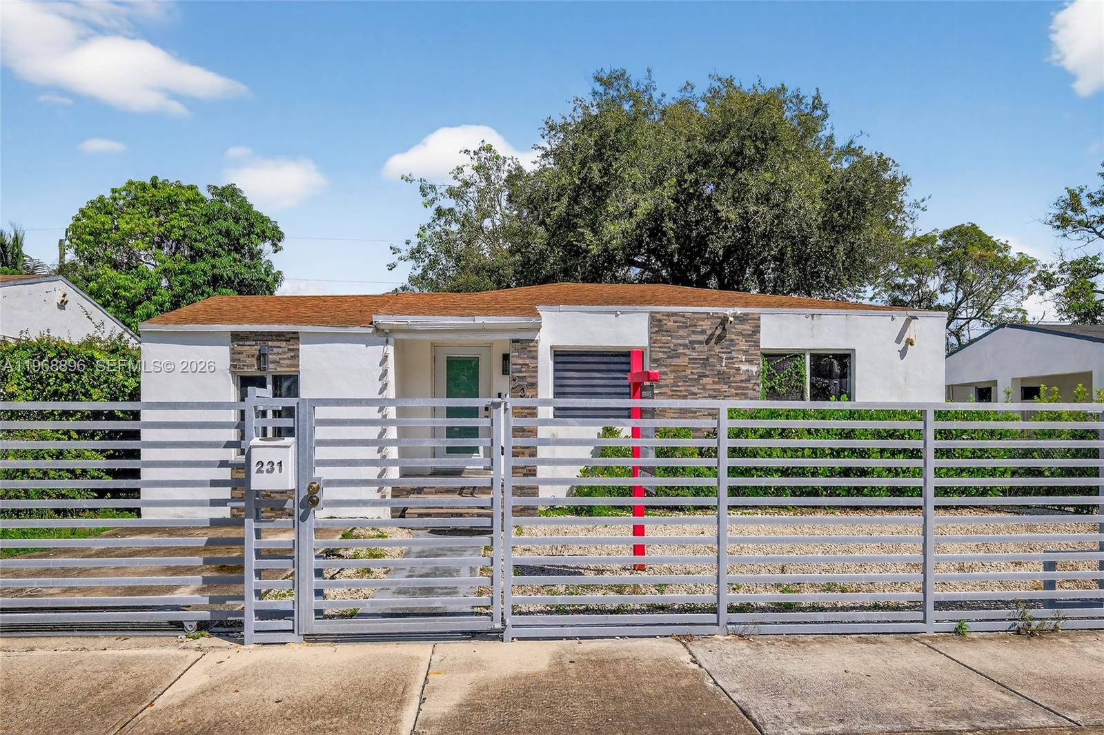 A modern kitchen features white upper cabinets, gray lower cabinets, and white marble-patterned countertops — 231 NW 44th St, Miami FL 33127, MIAMI, FL