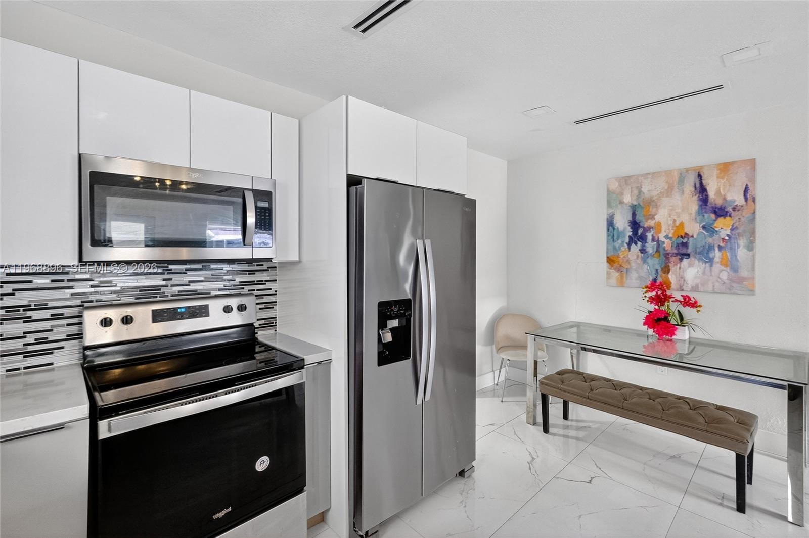 An open-concept living area features a kitchen island, dining space, and a blue sofa — 231 NW 44th St, Miami FL 33127, MIAMI, FL