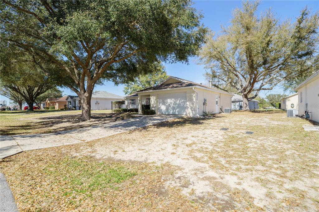 A single-story house with a white garage and a large tree in the front yard — 9859 SW 97TH LANE, OCALA, FL