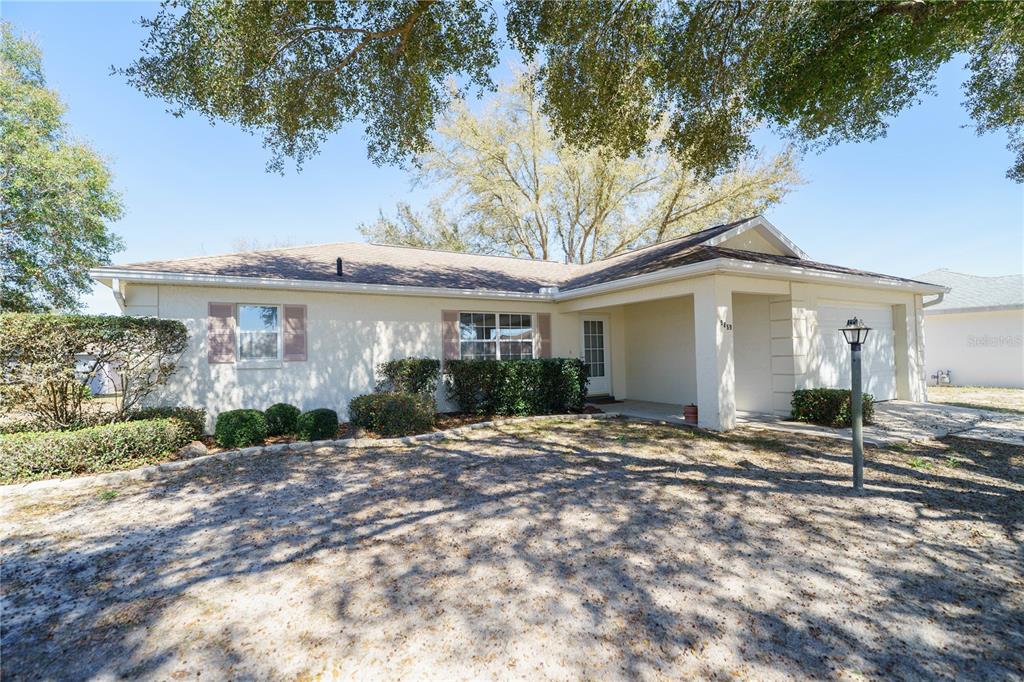 A single-story house with a beige exterior, a covered entryway, and a front-facing garage — 9859 SW 97TH LANE, OCALA, FL
