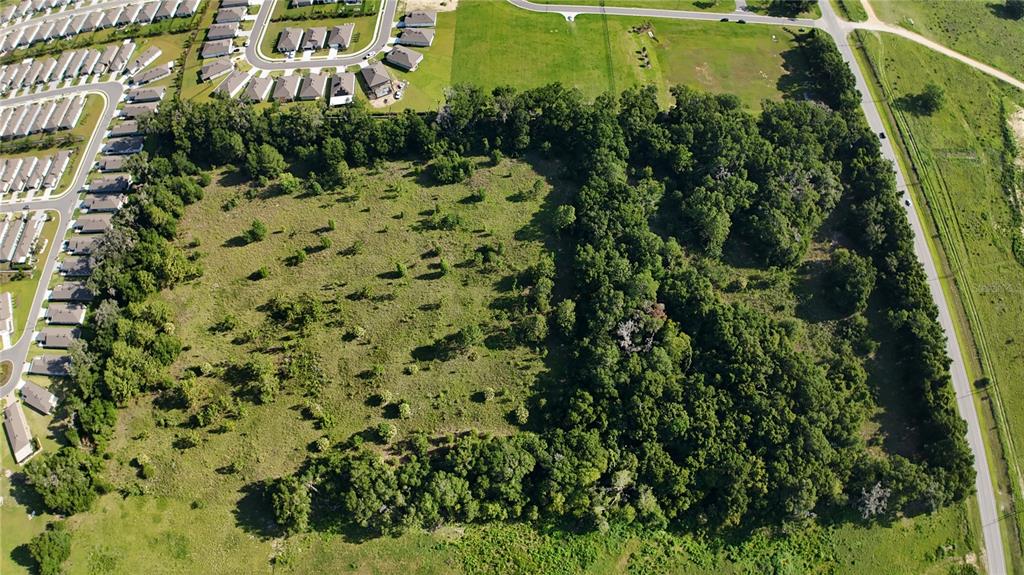 An aerial view shows a large, partially wooded plot of land adjacent to a residential neighborhood — XX SW 80TH AVENUE, OCALA, FL