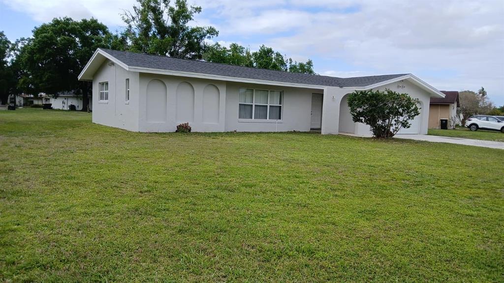 A single-story house with a light-colored exterior, a gray shingled roof, and a large lawn — 632 MIDIRON DRIVE, POINCIANA, FL