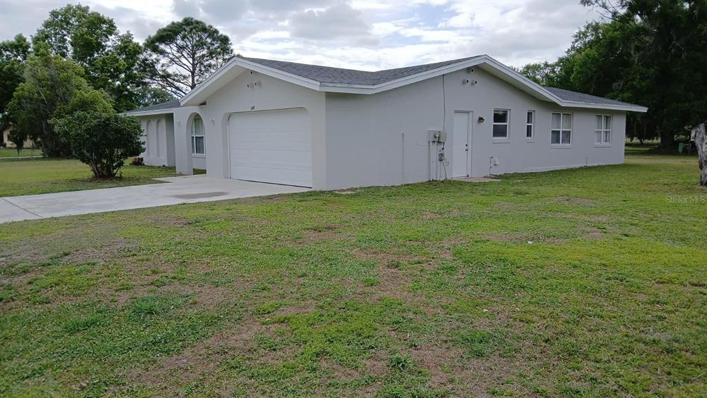 A single-story house with a white exterior, a two-car garage, and a large grassy yard — 632 MIDIRON DRIVE, POINCIANA, FL
