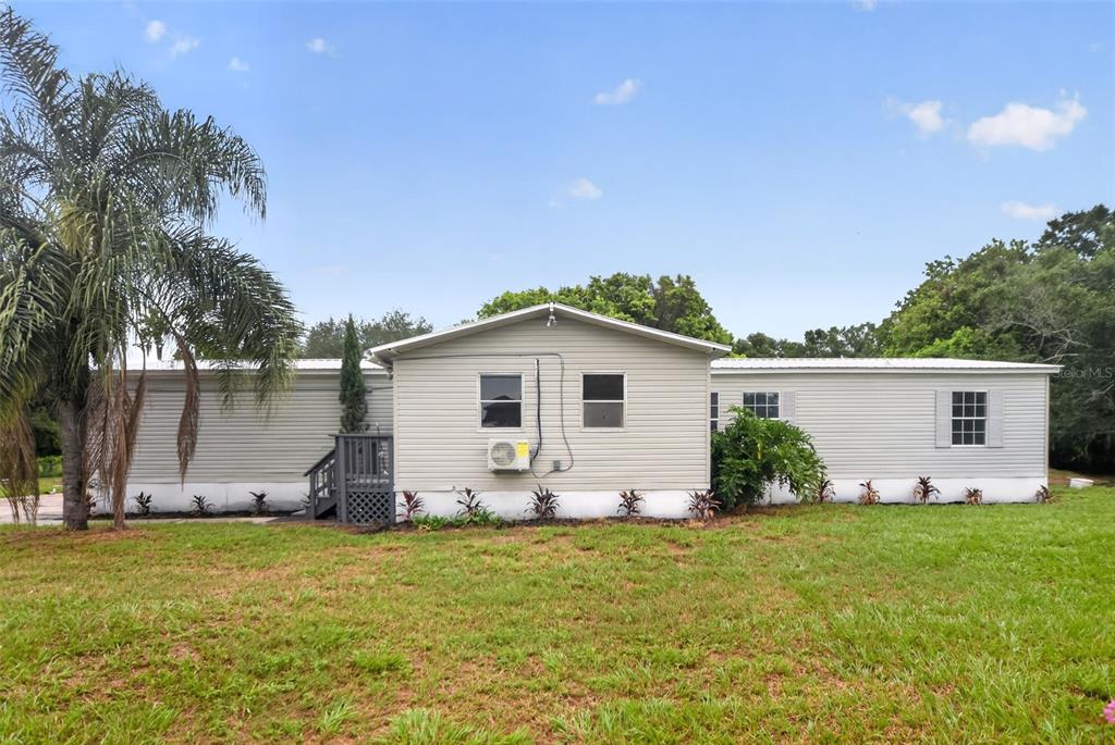 A single-story manufactured home with light siding, a small deck, and a palm tree — 10213 UNION PARK DRIVE, ORLANDO, FL