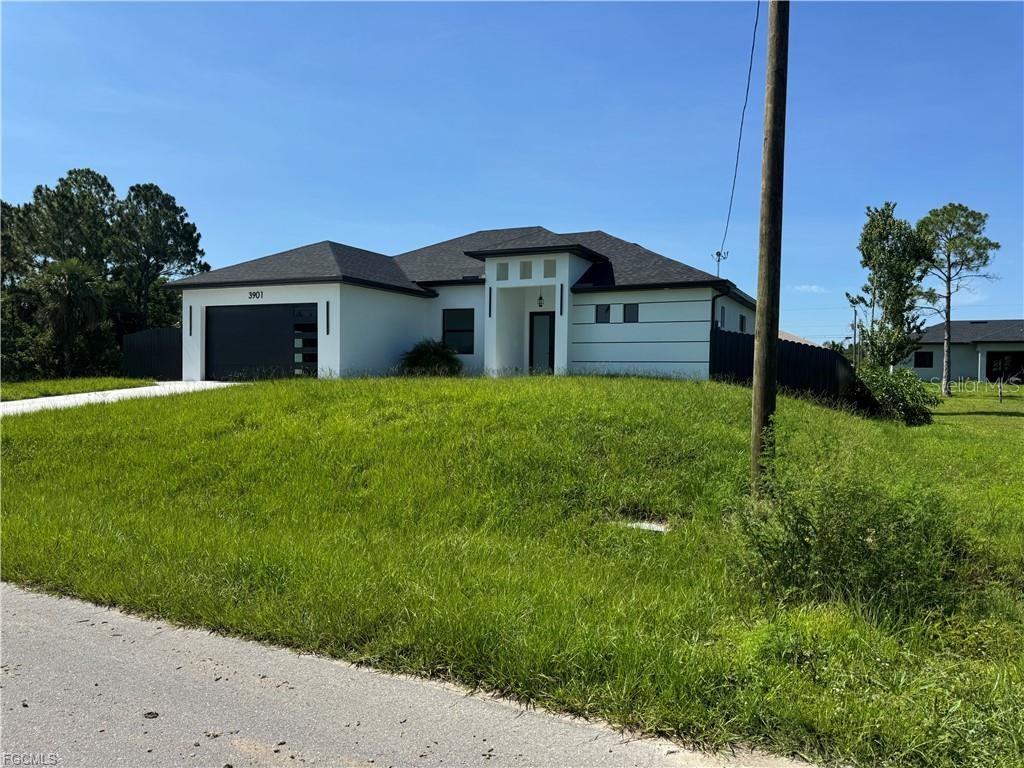 A modern single-story house with a white exterior, dark roof, and attached garage — 3901 3RD STREET SW, LEHIGH ACRES, FL
