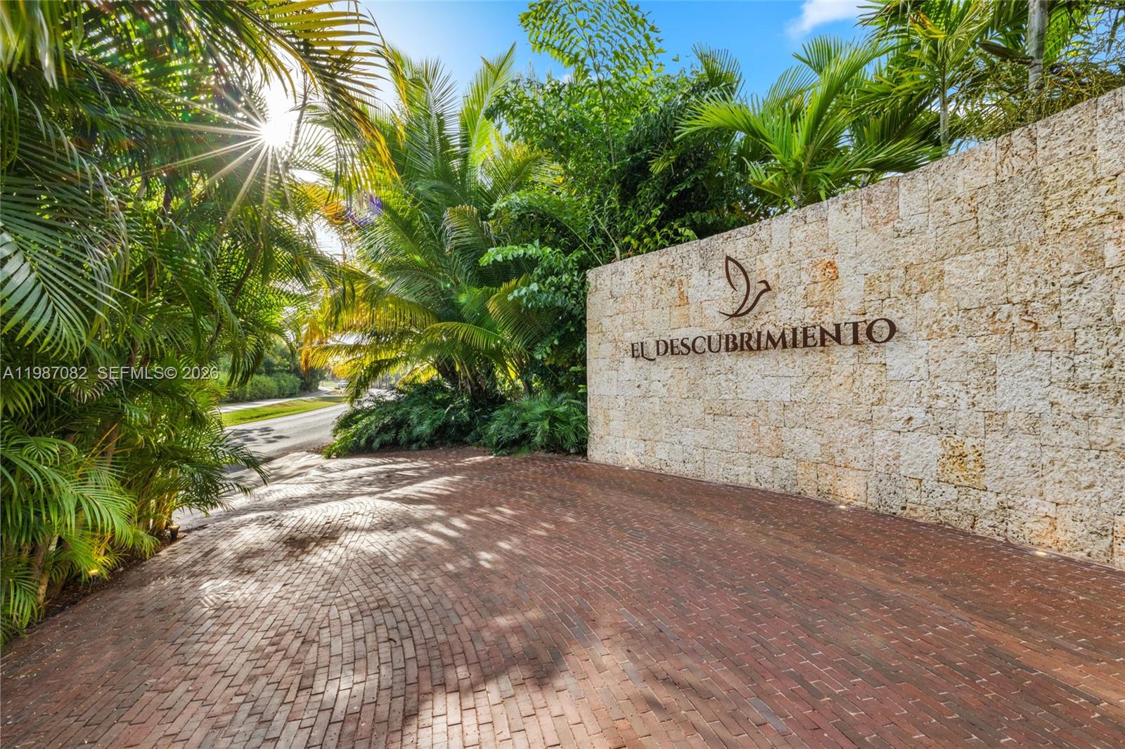 A stone wall with the name El Descubrimiento stands beside a brick driveway and palm trees — Las Palmas 21 A Casa de Campo, La Romana, Dominic, FL