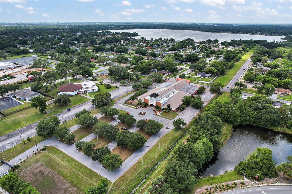An aerial view shows a large commercial building with a parking lot and surrounding greenery — 1 S COTTAGE HILL ROAD, ORLANDO, FL