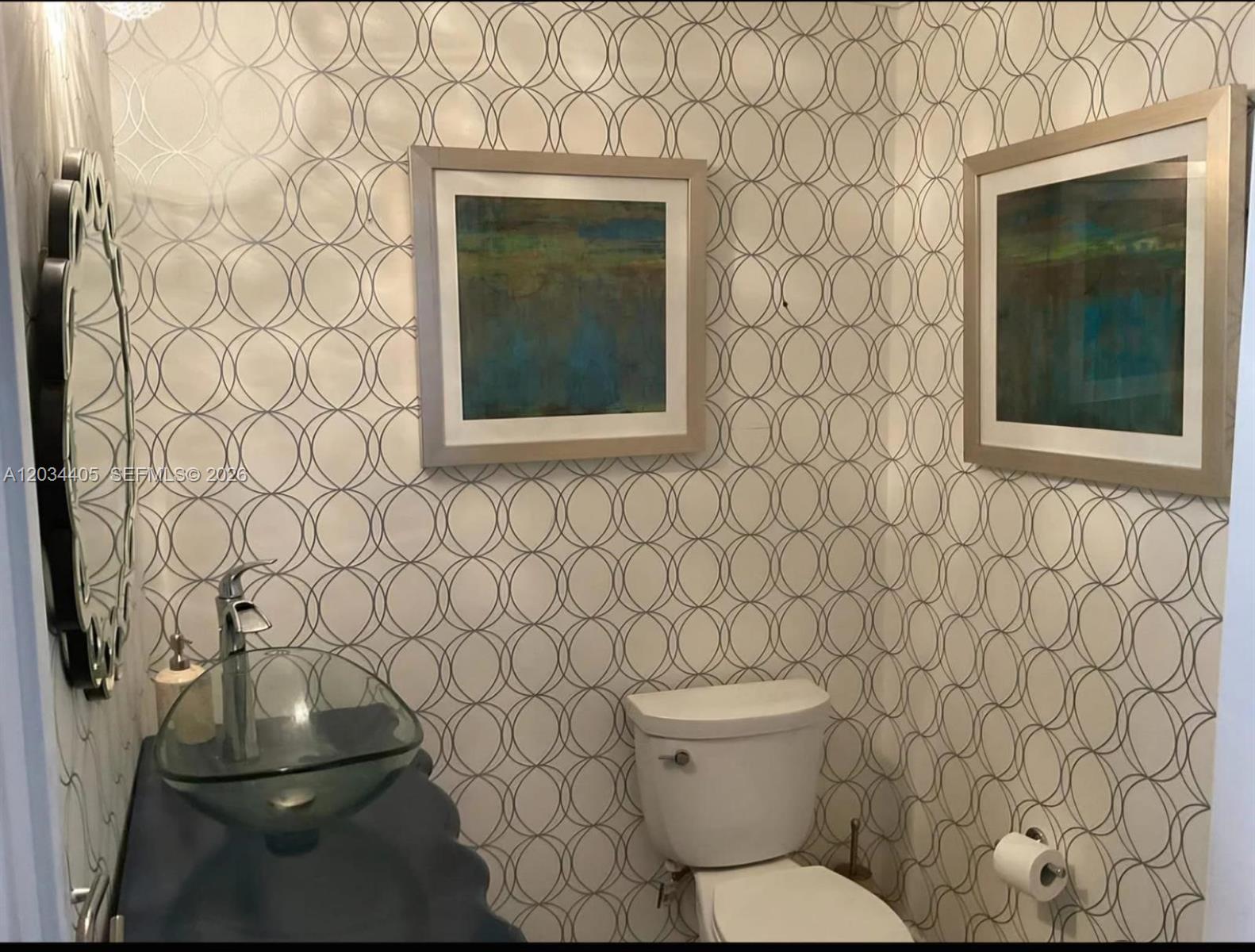 A powder room featuring patterned wallpaper, a glass vessel sink, and two framed wall pictures — 8682 Via Ancho Rd # 0, Boca Raton FL 33433, BOCA RATON, FL