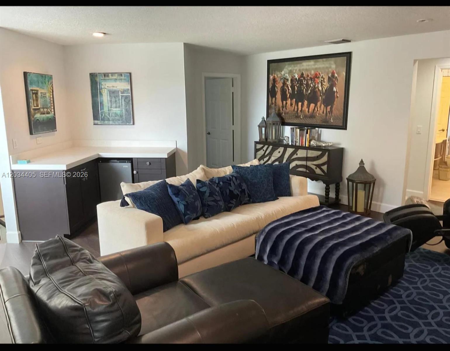 A living room features a white sofa with blue pillows, a dark leather chair, and a bar — 8682 Via Ancho Rd # 0, Boca Raton FL 33433, BOCA RATON, FL