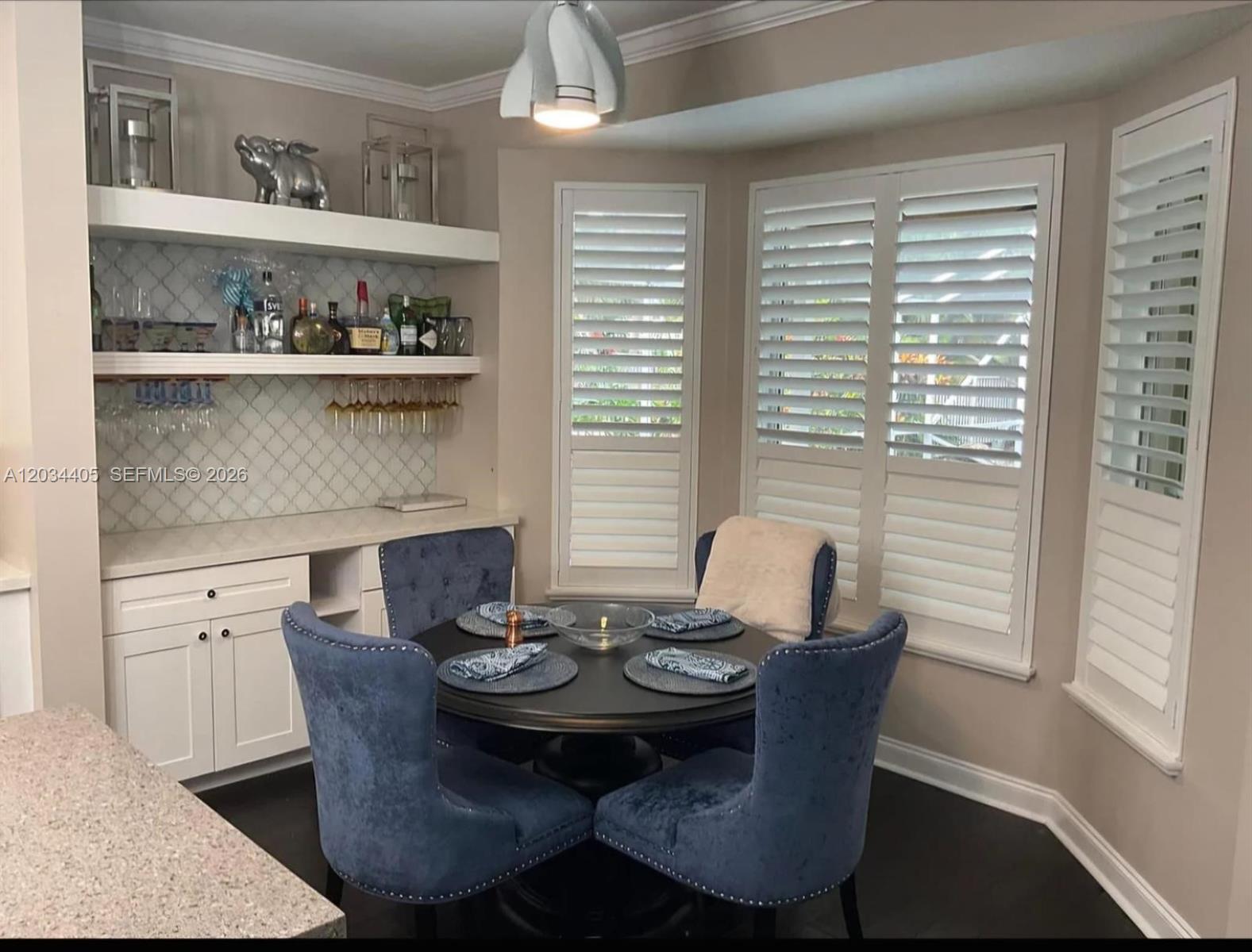 A dining area features a round table with blue chairs and a built-in wet bar — 8682 Via Ancho Rd # 0, Boca Raton FL 33433, BOCA RATON, FL
